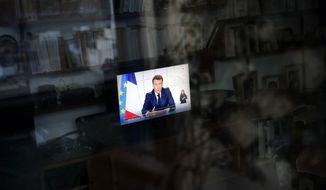 French President Emmanuel Macron gives a TV address to the nation on French TV channel TF1 in Paris, Wednesday, March 31, 2021. Macron has announced a three-week nationwide school closure and a month-long domestic travel ban in an effort to fight the rapid spread of the virus. (AP Photo/Christophe Ena)