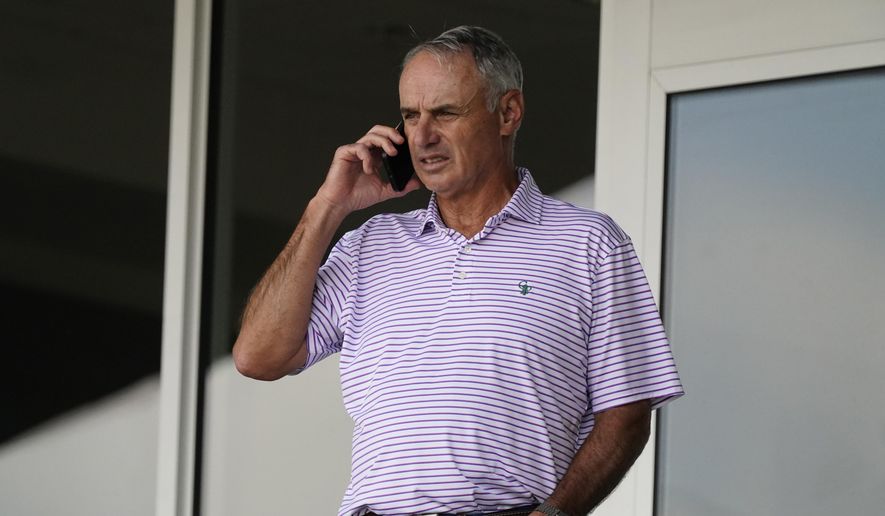 Major League Baseball Commissioner Rob Manfred speaks on his phone as he watches a spring training baseball game between the Atlanta Braves and Boston Red Sox on Wednesday, March 10, 2021, in Fort Myers, Fla. (AP Photo/John Bazemore) **FILE**