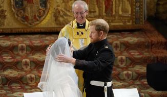 FILE - In this Saturday, May 19, 2018 file photo, Britain&#39;s Prince Harry pulls back the veil of Meghan Markle watched by Archbishop of Canterbury Justin Welby during their wedding at St. George&#39;s Chapel in Windsor Castle in Windsor, near London, England. The archbishop of Canterbury has confirmed that he married Prince Harry and Meghan Markle at Windsor Castle in May 2018, despite the couple’s claim they had another, private, ceremony three days earlier. During an interview with Oprah Winfrey earlier this month, Meghan said that “three days before our wedding we got married.” (Owen Humphreys/pool photo via AP, File)