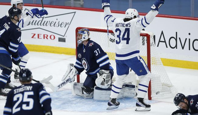 Toronto Maple Leafs&#x27; Auston Matthews (34) celebrates after scoring on Winnipeg Jets goaltender Connor Hellebuyck (37) during the first period of an NHL hockey game Wednesday, March 31, 2021, in Winnipeg, Manitoba. (John Woods/The Canadian Press via AP)