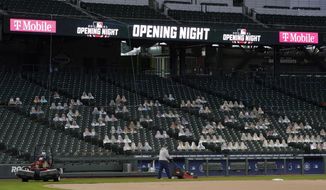 Grounds crew workers mow near the first-base foul line at T-Mobile Park, the home of the Seattle Mariners baseball team, Monday, March 22, 2021, in Seattle as photos in the stands demonstrate how fans attending reduced-capacity games will be separated into &amp;quot;seating pods&amp;quot; to avoid the spread of COVID-19. The Mariners are scheduled host the San Francisco Giants on April 1 in the Mariners&#39; home-opener. (AP Photo/Ted S. Warren)