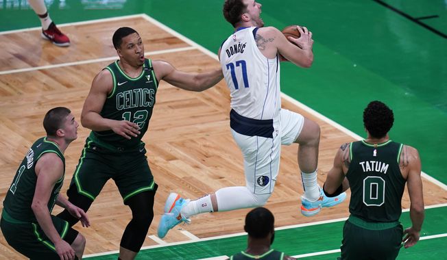 Dallas Mavericks guard Luka Doncic (77) drives through the Boston Celtics&#x27;s defense during the first half of an NBA basketball game Wednesday, March 31, 2021, in Boston. (AP Photo/Charles Krupa)
