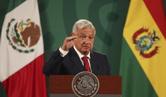 Mexican President Andrés Manuel López Obrador gives his daily, morning press conference at the National Palace, where a Bolivian flag stands behind due to the presence of visiting Bolivian President Luis Arce in Mexico City, Wednesday, March 24, 2021.(AP Photo/Marco Ugarte)