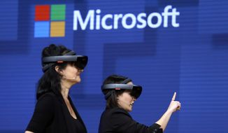 In this May 11, 2017, file photo, members of a design team at Cirque du Soleil demonstrate use of Microsoft&#39;s HoloLens device in helping to virtually design a set at the Microsoft Build 2017 developers conference in Seattle. Microsoft says it has won a nearly $22 billion contract to supply U.S. Army combat troops with its virtual reality headsets. Microsoft announced the deal Wednesday, March 31, 2021. (AP Photo/Elaine Thompson, File)