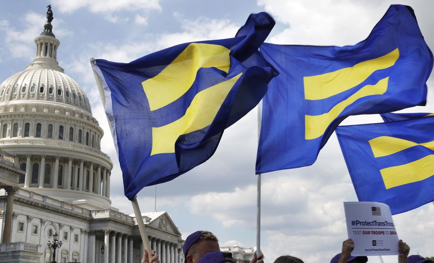 In this July 26, 2017 file photo, people with the Human Rights Campaign hold up &quot;equality flags&quot; during an event on Capitol Hill in Washington, in support of transgender members of the military. Defense officials say the Pentagon will sweep away Trump-era policies that largely banned transgender people from serving in the military and will issue new rules that broaden their access to medical care and gender transition. (AP Photo/Jacquelyn Martin, File)