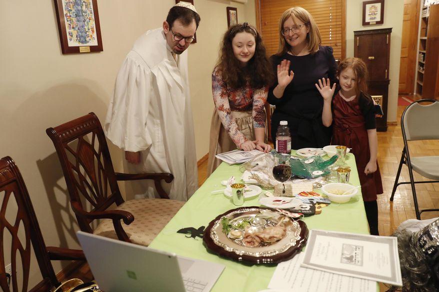 In this Wednesday, April 8, 2020, file photo, Rabbi Shlomo Segal, left, and his family wave goodbye to participants after he conducted a virtual Passover seder for members of his congregation, friends and family broadcast on YouTube from his home in the Sheepshead Bay neighborhood of Brooklyn during the current coronavirus outbreak in New York. From left, are Segal; daughter Shira, 12; wife, Adina, and daughter, Rayna, 8. In 2021, the Sabbath led directly into Passover, limiting the use of technology for Segal and his congregants. Instead of streaming their seder, the synagogue provided online workshops prior to Passover so families could do it on their own. Segal says that many of his members are still reluctant to gather together in person. (AP Photo/Kathy Willens)