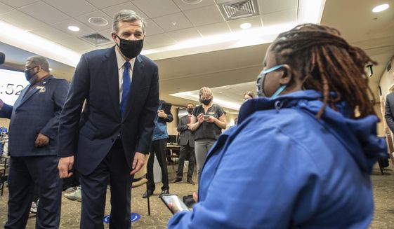 Gov. Roy Cooper, left, asks a patient how her vaccine went at CaroMont Health in Gastonia, N.C., on Wednesday, March 31, 2021. (Khadejeh Nikouyeh/The News &amp;amp; Observer via AP)
