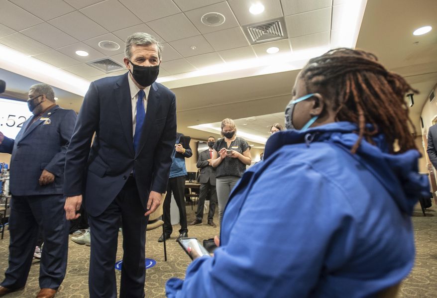 Gov. Roy Cooper, left, asks a patient how her vaccine went at CaroMont Health in Gastonia, N.C., on Wednesday, March 31, 2021. (Khadejeh Nikouyeh/The News & Observer via AP)
