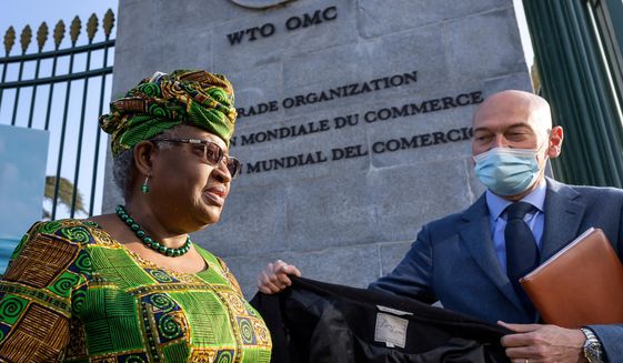 FILE - In this Monday, March 1, 2021 file photo, New Director-General of the World Trade Organisation Ngozi Okonjo-Iweala, left, walks at the entrance of the WTO, following a photo-op upon her arrival at the WTO headquarters to take office in Geneva, Switzerland. The World Trade Organization is raising its estimate for the rebound in global trade in goods but warning that the COVID-19 pandemic still poses the greatest threat to a recovery that is being hampered by lagging vaccinations, regional disparities and weakness in services. The organizations&#39; WTO Director-General Ngozi Okonjo-Iweala called for a better access to vaccines for people in in poorer countries. (Fabrice Coffrini/Pool/Keystone via AP, FIle)
