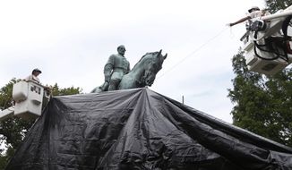 FILE - In this Wednesday, Aug. 23, 2017 file photo, city workers drape a tarp over a statue of Confederate Gen. Robert E. Lee in Emancipation park in Charlottesville, Va., intended to symbolize the city&#39;s mourning for Heather Heyer who was killed while protesting a white nationalist rally earlier in the month. On Thursday, April 1, 2021, Virginia&#39;s highest court ruled that the city of Charlottesville can take down this and another statue of a Confederate general. (AP Photo/Steve Helber, File)