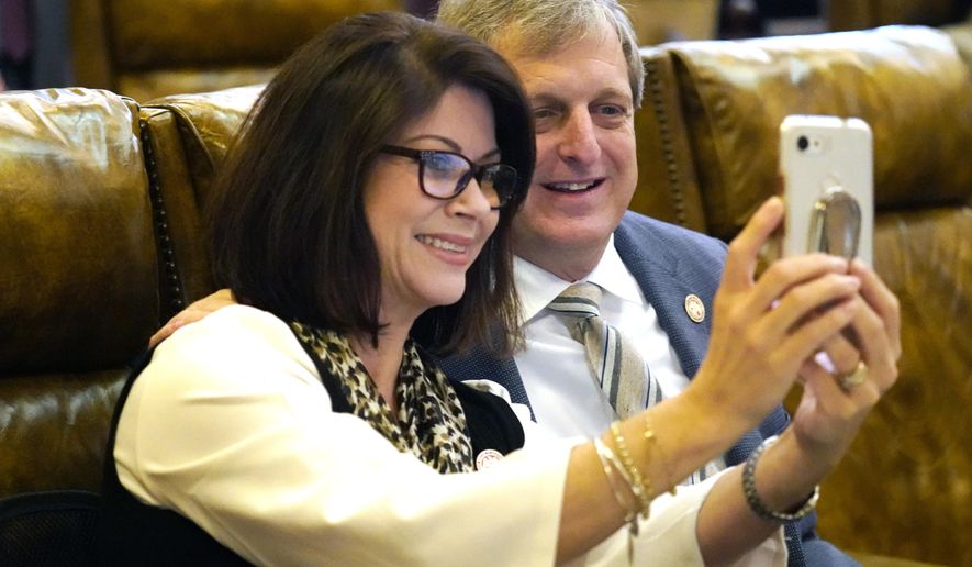 Republican Reps. Carolyn Crawford of Pass Christian, left, and Donnie Scoggin of Ellisville, smile for a "selfie" photograph during a recess in the House, Wednesday, March 31, 2021 at the the Capitol in Jackson, Miss. Lawmakers in both chambers worked steadily to meet deadlines on the remaining legislation to be completed this session and are expected to Sine Die on Thursday. (AP Photo/Rogelio V. Solis)