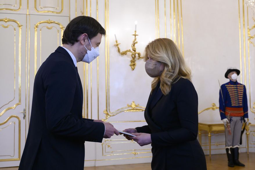 Slovakia's President Zuzana Caputova, right, tasks Vice-premier Eduard Heger with forming a new government at the Presidential Palace in Bratislava, Slovakia, on Tuesday, March 30, 2021. Slovakia’s prime minister and his government resigned to end the political crisis triggered by a secret deal to buy Russia’s Sputnik V coronavirus vaccine.(Pavel Neubauer/TASR via AP)