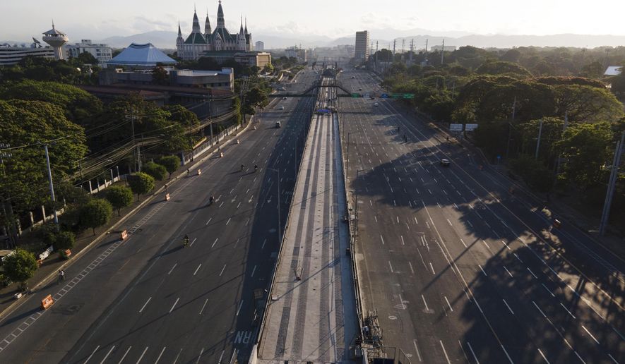 Motorist traverse an almost empty Commonwealth Avenue as the government implements a strict lockdown to prevent the spread of the coronavirus on Good Friday, April 2, 2021 in Quezon city, Philippines. Filipinos marked Jesus Christ's crucifixion Friday in one of the most solemn holidays in Asia's largest Catholic nation which combined with a weeklong coronavirus lockdown to empty Manila's streets of crowds and heavy traffic jams. Major highways and roads were eerily quiet on Good Friday and churches were deserted too after religious gatherings were prohibited in metropolitan Manila and four outlying provinces. (AP Photo/Aaron Favila)