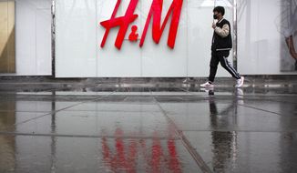 FILE - In this March 26, 2021, file photo, a man carrying an umbrella walks past an H&amp;amp;M clothing store at a shopping mall in Beijing. Chinese regulators on Friday, April 2, 2021, said H&amp;amp;M has agreed to change a “problem map” online following government criticism, adding to pressure on the Swedish retailer amid a conflict with Western governments over Chinese policies in its Xinjiang region. (AP Photo/Mark Schiefelbein, File)
