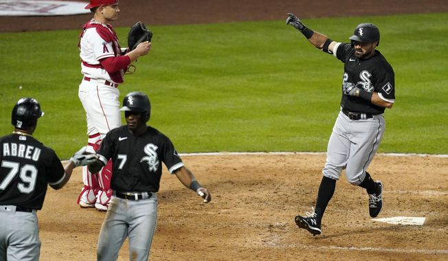 Chicago White Sox&#x27;s Adam Eaton, right, scores after hitting a two-run home run as shortstop Tim Anderson, second from right, is congratulated by Jose Abreu, left, and Los Angeles Angels catcher Max Stassi watches during the fifth inning of an Opening Day baseball game Thursday, April 1, 2021, in Anaheim, Calif. (AP Photo/Mark J. Terrill)