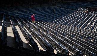 A Philadelphia Phillies usher walks through the empty stands before the start of a baseball game against the Atlanta Braves, Saturday, April 3, 2021, in Philadelphia. (AP Photo/Laurence Kesterson)