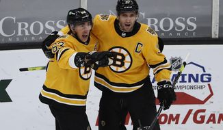 Boston Bruins&#39; Patrice Bergeron, right, celebrates with Brad Marchand, left, after Marchand scored against the Pittsburgh Penguins during the second period of an NHL hockey game Saturday, April 3, 2021, in Boston. (AP Photo/Winslow Townson)