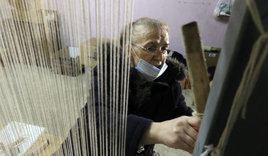 Hate Ora, 64, or 'Aunt Hate' as everyone knows her, weaving a carpet in Kukes town, northeastern Albania, Friday, March 12, 2021. Albania once had 13 former state-run factories that produced carpets, rugs, fez hats, felt folk costumes and other handicrafts. Kukes, a town northeast of the capital, Tirana, alone employed more than 1,200 women as weavers. When the country's communist era ended in 1990, the local factory closed. (AP Photo/Hektor Pustina)
