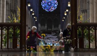 Washington National Cathedral Altar Guild members Anne Bowen, left, and Anne Roulhac, right, arrange flowers in preparation for the virtual Easter Sunday worship services at the Washington National Cathedral in Washington, Saturday, April 3, 2021. The Washington National Cathedral offers online worship services because of the COVID-19 pandemic. (AP Photo/Carolyn Kaster) ** FILE **