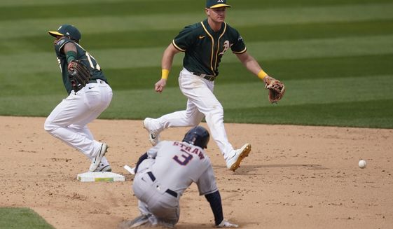 Oakland Athletics shortstop Elvis Andrus, left, cannot field a throwing error by third baseman Matt Chapman, top, as Houston Astros&#39; Myles Straw (3) advances to second base during the sixth inning of a baseball game in Oakland, Calif., Sunday, April 4, 2021. (AP Photo/Jeff Chiu)