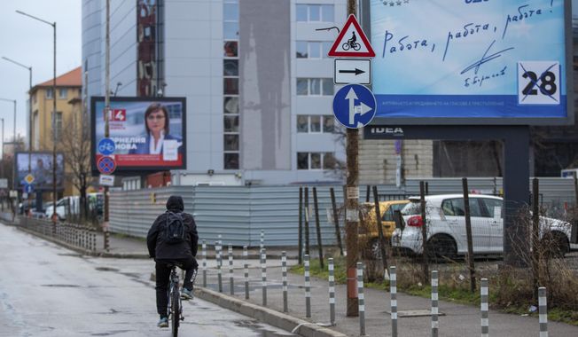 A cyclist passes by election poster of two rival parties in capital Sofia, Bulgaria on Saturday, April 3, 2021. After months of nationwide anti-government protests over corruption, stalled reforms and a stagnating economy in the EU&#x27;s poorest member state, Bulgarians are gearing up for a parliamentary election in the shadow of the coronavirus pandemic. (AP Photo/Visar Kryeziu)