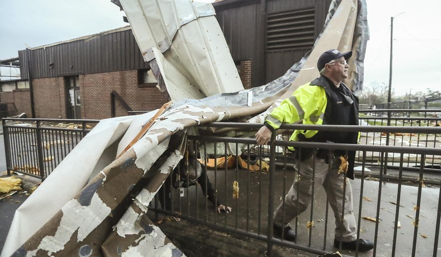 An officer moves near debris at Newnan High School, in Newnan, in Coweta County, Ga. on Friday, March 26, 2021, after a tornado moved through the area. Meteorologists say one large, dangerous tornado moved through western Georgia early Friday, downing trees and power lines. (John Spink/Atlanta Journal-Constitution via AP)