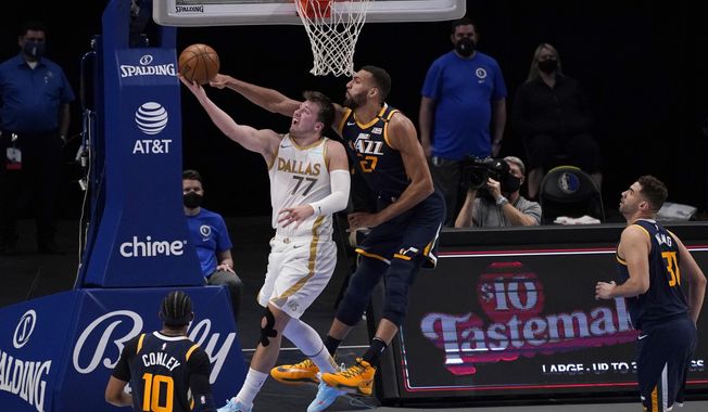 Dallas Mavericks guard Luka Doncic (77) goes up to shoot as Utah Jazz center Rudy Gobert, center right, defends in the first half of an NBA basketball game in Dallas, Monday April 5, 2021. Jazz&#x27;s Mike Conley and Georges Niang look on. (AP Photo/Tony Gutierrez)