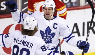 Toronto Maple Leafs&#39; John Tavares, center, celebrates his goal with teammate William Nylander during the third period of an NHL hockey game against the Calgary Flames, in Calgary, Alberta, Sunday, April 4, 2021. (Larry MacDougal/The Canadian Press via AP)