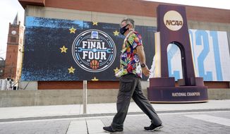 A pedestrian walks past a mock championship trophy before Baylor plays Gonzaga in the NCAA tournament championship basketball game at Lucas Oil Stadium in Indianapolis, Monday, April 5, 2021. (AP Photo/AJ Mast)