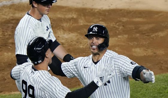 New York Yankees Aaron Judge, (99) celebrates with designated hitter Giancarlo Stanton after scoring on Stanton&#39;s fifth-inning grand slam in a baseball game against the Baltimore Orioles, Monday, April 5, 2021, at Yankee Stadium in New York. Yankees&#39; DJ LeMahieu passes behind the pair. (AP Photo/Kathy Willens)