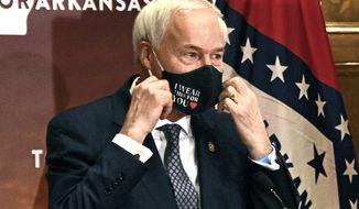 FILE - In this July 20, 2020 file photo, Arkansas Gov. Asa Hutchinson removes his mask before a briefing at the state capitol in Little Rock. Gov. Hutchinson on Monday, April 5, 2021 vetoed legislation that would have made his state the first to ban gender confirming treatments or surgery for transgender youth. (Staci Vandagriff/The Arkansas Democrat-Gazette via AP, File)