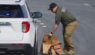 A sheriff&#39;s deputy from Frederick County, Md., puts paper bags with evidence into a police vehicle near the scene of a shooting at a business park in Frederick, Md., Tuesday, April 6, 2021. (AP Photo/Julio Cortez)