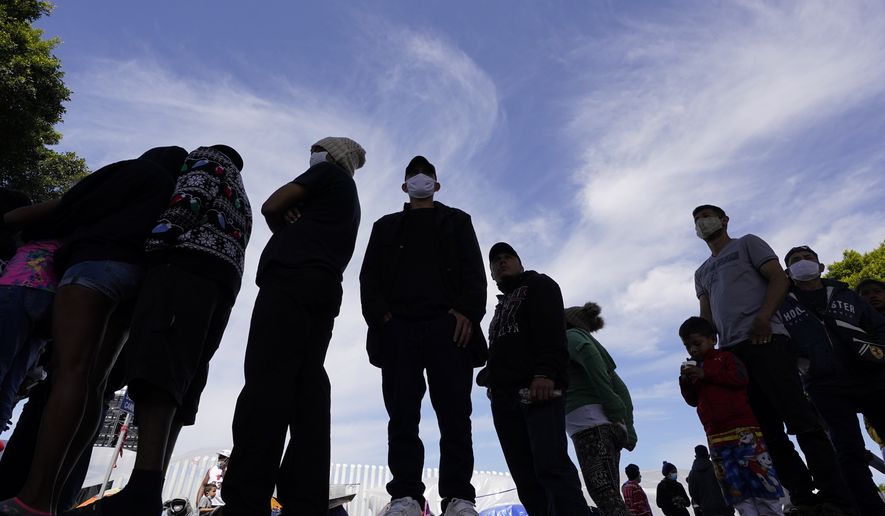 Migrants line up for a free meal at a makeshift camp of migrants at the border port of entry leading to the United States, Wednesday, March 17, 2021, in Tijuana, Mexico. (AP Photo/Gregory Bull) **FILE**