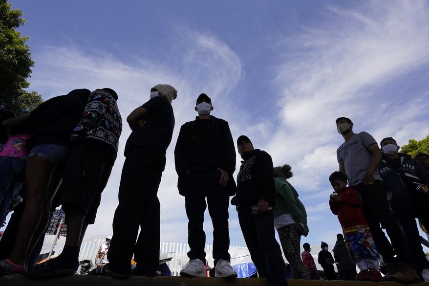 Migrants line up for a free meal at a makeshift camp of migrants at the border port of entry leading to the United States, Wednesday, March 17, 2021, in Tijuana, Mexico. (AP Photo/Gregory Bull) **FILE**