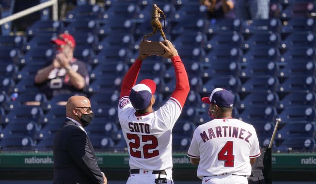 Washington Nationals right fielder Juan Soto (22) holds up his 2020 National League batting title trophy alongside general manager Mike Rizzo, left, and manager Dave Martinez before an opening day baseball game against the Atlanta Braves at Nationals Park, Tuesday, April 6, 2021, in Washington. (AP Photo/Alex Brandon)