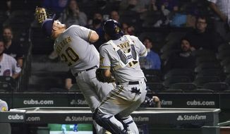 Milwaukee Brewers first baseman Daniel Vogelbach (20) catches a foul ball hit by Chicago Cubs&#x27; Jason Heyward as catcher Omar Narvaez (10) also chases it during the fifth inning of a baseball game Tuesday, April 6, 2021, in Chicago. (AP Photo/David Banks)