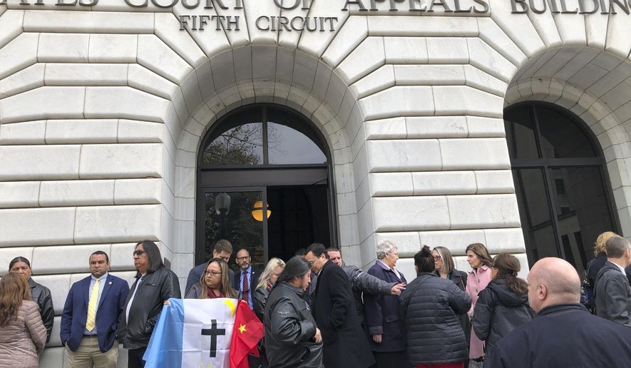 FILE - Rosa Soto Alvarez, of Tucson,, holds a flag of the Pascua Yaqui Tribe as she and other Native Americans stand outside the federal appeals court in New Orleans, Wednesday, Jan. 22, 2020. Parts of a federal law giving Native American families preference in the adoption of Native American children were effectively struck down Tuesday, April 6, 2021 by a sharply divided federal appeals court, a defeat for tribal leaders who said the 1978 law was important to protecting their families and culture. (AP Photo/Kevin McGill)