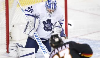 Toronto Maple Leafs goalie Jack Campbell, top, makes a save against Calgary Flames&#39; Sean Monahan during second-period NHL hockey game action in Calgary, Alberta, Monday, April 5, 2021. (Larry MacDougal/The Canadian Press via AP)