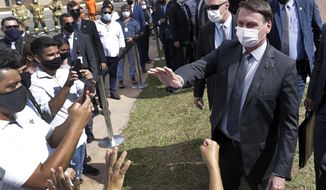 Wearing a mask to curb the spread of the new coronavirus, Brazil&#39;s President Jair Bolsonaro greets people after a ceremony to deliver affordable homes built by the government, in a neighborhood of Brasilia, Brazil, Monday, Apr. 5, 2021. (AP Photo/Eraldo Peres)