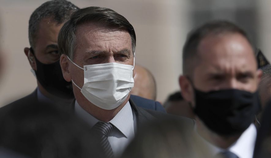 Wearing a mask to curb the spread of the new coronavirus, Brazil&#x27;s President Jair Bolsonaro arrives for a ceremony to deliver affordable homes built by the government, in a neighborhood of Brasilia, Brazil, Monday, Apr. 5, 2021. (AP Photo/Eraldo Peres)