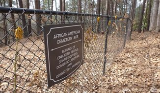 Flowers adorn a fence marking an African American cemetery site at Woodland Cemetery in Clemson, South Carolina on Sunday, Feb.  28, 2021.   Students at Clemson University who found an unkempt graveyard on campus last year sparked the discovery of more than 600 unmarked graves most likely belonging to enslaved Black people, sharecroppers and convicted laborers. The revelation has Clemson working to identify the dead and properly honor them amid a national reckoning by universities about their legacies of racial injustice.  (AP Photo/Michelle Liu)