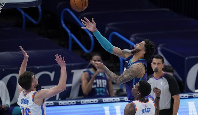 Charlotte Hornets forward Miles Bridges, rear, shoots in front of Oklahoma City Thunder guard Ty Jerome (16) and forward Jaylen Hoard (8) in the first half of an NBA basketball game Wednesday, April 7, 2021, in Oklahoma City. (AP Photo/Sue Ogrocki)