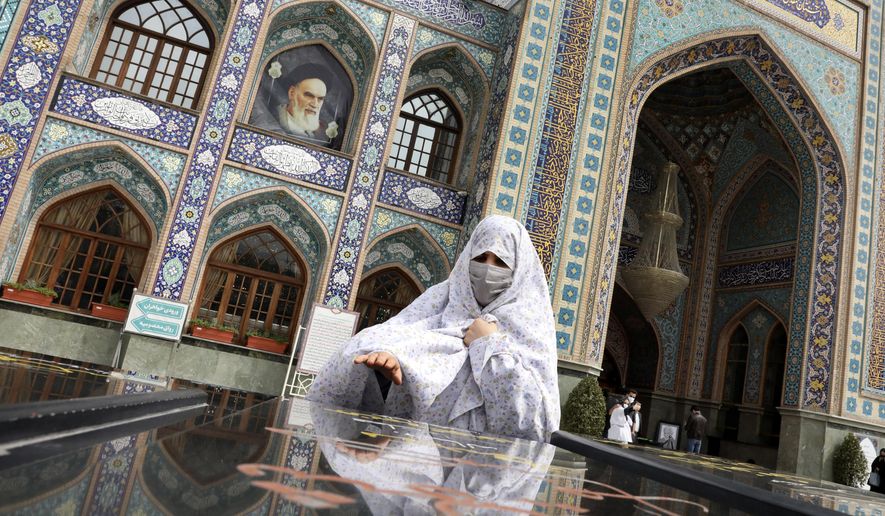 A woman prays at the grave of an unknown soldier who was killed during 1980-88 Iran-Iraq war, at the shrine of Saint Saleh in northern Tehran, Iran, Tuesday, April 6, 2021. .(AP Photo/Vahid Salemi)