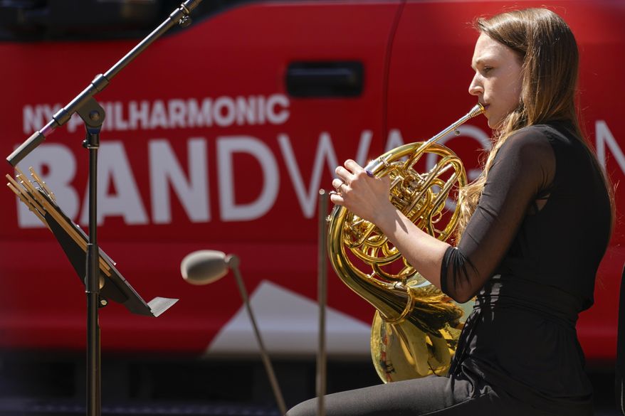 A member of the New York Philharmonic performs on the Lincoln Center campus as part of Restart Stages at Lincoln Center, Wednesday, April 7, 2021, in New York. Members of the New York Philharmonic gave an outdoor concert at Lincoln Center for heath care workers, 13 months after the novel coronavirus pandemic decimated their season. (AP Photo/Mary Altaffer)