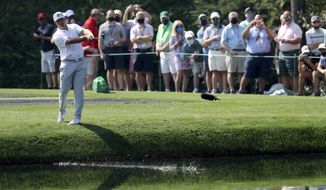 Patrons watches as Bryson DeChambeau skip his ball across the pond to the 16th green during a practice round for the Masters golf tournament at Augusta National Golf Club on Wednesday, April 7, 2021, in Augusta, Ga. (Curtis Compton/Atlanta Journal-Constitution via AP)