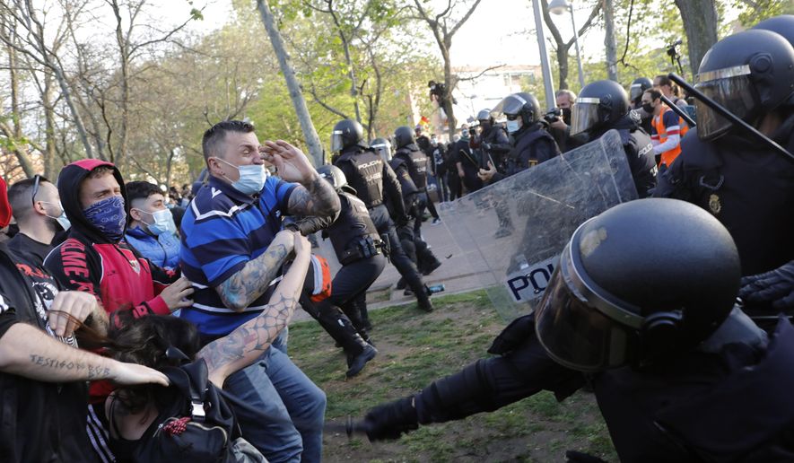 Spanish police use batons to keep protesters away from supporters of the far-right Vox party during a party rally in Madrid's Vallecas neigborhood, a traditional left-wing bastion, Spain, Wednesday, April 7, 2021. Scuffles started when the national leader of Vox, Santiago Abascal, approached a crowd which had gathered to protest the party rally. Riot peace charged the bunches of protesters to keep them away from Abascal and other members of his party campaigning for upcoming regional elections in the area including Spain's capital. (AP Photo/Bernat Armangue)