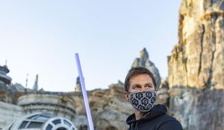In this photo provided by Walt Disney World, NFL star Tom Brady visits Star Wars: Galaxy&#39;s Edge inside Disney&#39;s Hollywood Studios at Walt Disney World Resort in Lake Buena Vista, Fla., Monday, April 5, 2021. A mask-wearing Brady visited the Star Wars-themed section of Walt Disney World with his family and friends, two months after he led the Bucs to a Super Bowl win against the Chiefs. (Matt Stroshane/Disney World via AP)