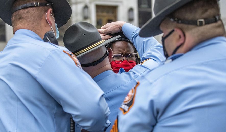 FILE-In this Thursday, March 25, 2021 file photo, State Rep. Park Cannon, D-Atlanta, is placed into the back of a Georgia State Capitol patrol car after being arrested by Georgia State Troopers at the Georgia State Capitol Building in Atlanta. Cannon was arrested by Capitol police after she attempted to knock on the door of the Gov. Brian Kemp office during his remarks after he signed into law a sweeping Republican-sponsored overhaul of state elections. The Fulton County District attorney won't prosecute Cannon, announced Wednesday, April 7, 2021, who was arrested for knocking on the governor's door during a voting bill signing. (Alyssa Pointer/Atlanta Journal-Constitution via AP, File)