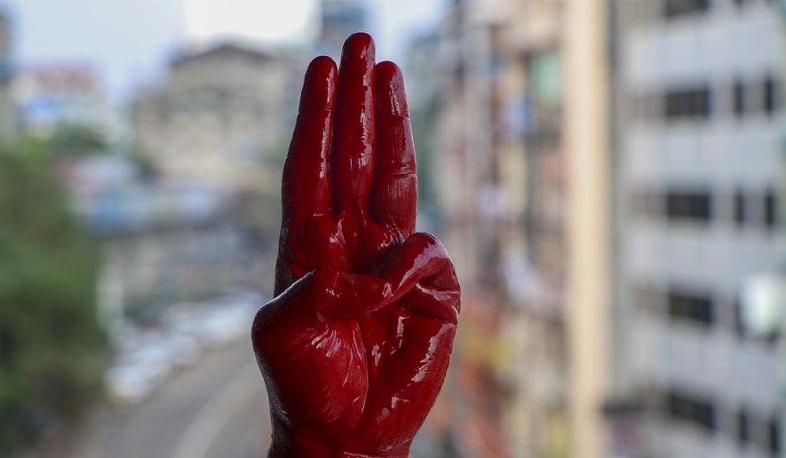 An anti-coup protester shows the three fingered salute of resistance on his red painted hand in memory of protesters who lost their lives during previous demonstrations in Yangon, Myanmar on Tuesday, April 6, 2021. Threats of lethal violence and arrests of protesters have failed to suppress daily demonstrations across Myanmar demanding the military step down and reinstate the democratically elected government. (AP Photo)