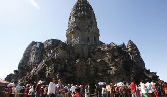 FILE - In this Sunday, Dec. 31, 2017, file photo, tourists line up for stepping up Angkor Wat temple outside Siem Reap, Cambodia. Cambodia is closing the Angkor temple complex to visitors because of a growing COVID-19 outbreak. The temples at Angkor, built between the 9th and 15th centuries, are Cambodia’s biggest tourist attraction, though the pandemic has reduced the number of visitors dramatically. The Apsara Authority that oversees the site says the ban on visitors will last until April 20. (AP Photo/Heng Sinith, File)